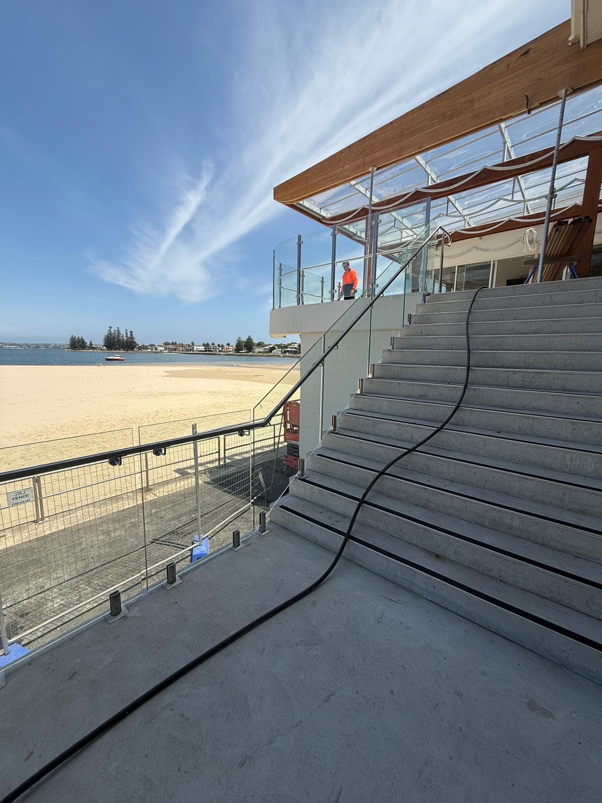 Glass balustrade with handrail on wide external stair by beach, Sans Souci